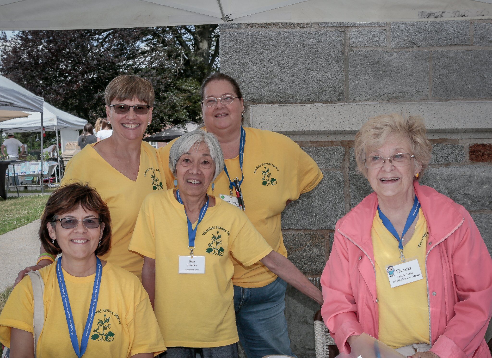 five smiling women wearing yellow t-shirts