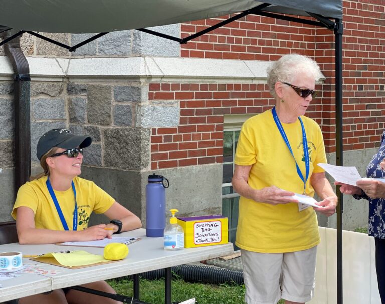 two female volunteers wearing sunglasses and yellow shirts