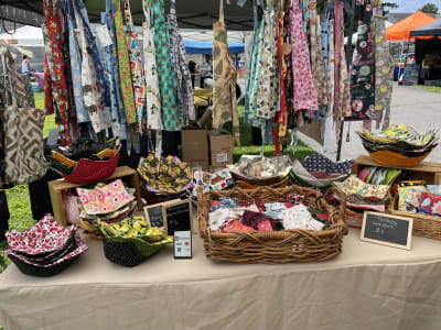 Multi colored aprons hanging behind a table of textile goods