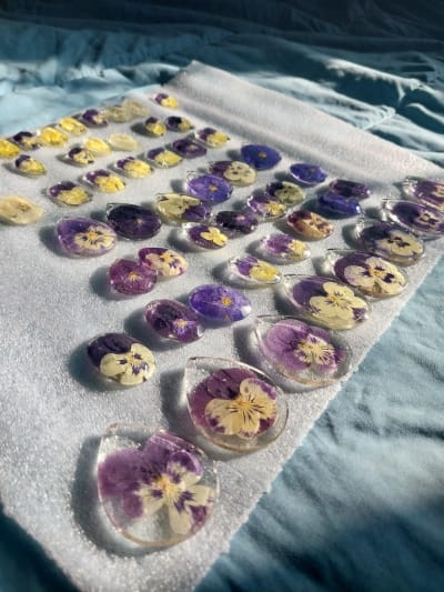Display of resin pendants containing purple and yellow pansies