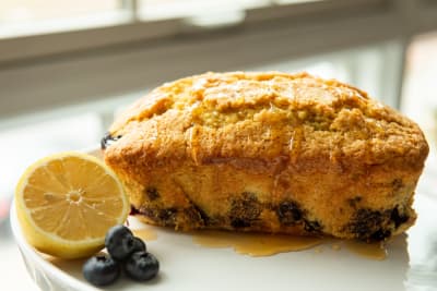 blueberry lemon scone on white plate with half of a lemon and several blueberries